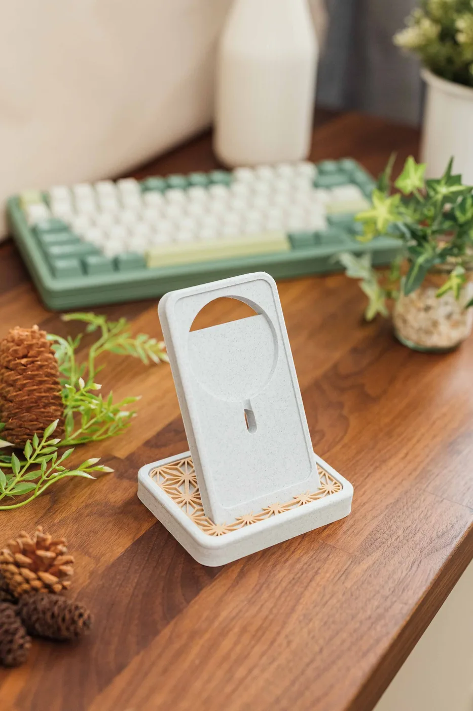 A 3D printed phone stand on a desk beside a keyboard.