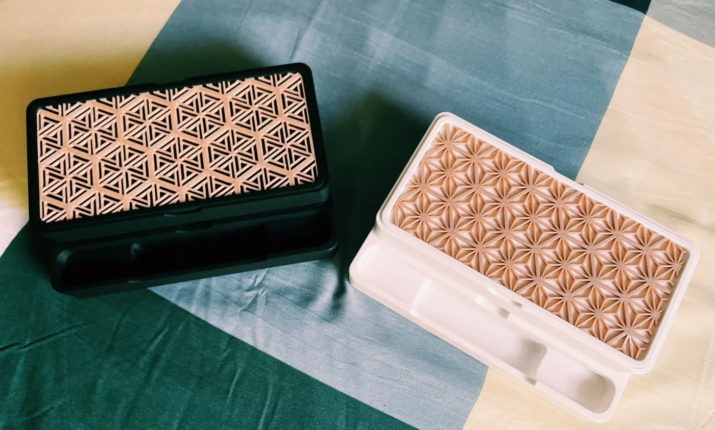 A 3D printed kumiko-pattern organiser on a wooden desk.